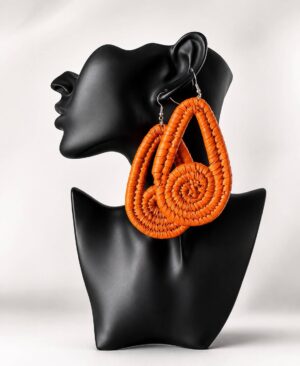 Pair of large, handmade woven orange statement teardrop earrings with spiral centerpieces displayed on a black mannequin bust.