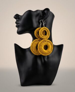 Pair of handmade tiered double-hoop statement earrings in woven mustard yellow fiber displayed on a black bust mannequin.