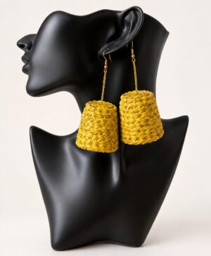 Pair of handmade mustard yellow woven straw statement raffia drop earrings displayed on a black mannequin bust against a white background.