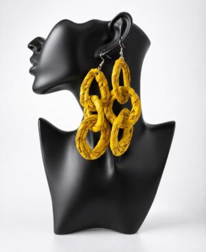 Pair of large, handcrafted mustard yellow woven multi-link statement drop earrings displayed on a matte black female mannequin bust.