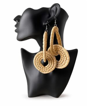 Pair of large handmade woven straw statement drop earrings in natural beige displayed on a black mannequin bust against a white background.