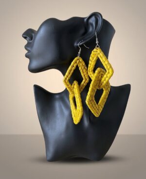 Pair of handmade mustard yellow woven natural fiber interlocking double-diamond statement drop earrings displayed on a black mannequin bust profile.