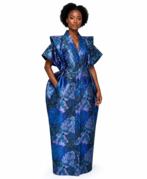 Model wearing a structured cobalt blue and purple metallic floral brocade maxi dress with exaggerated shoulders.