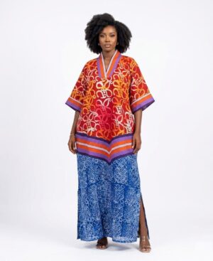 Woman wearing a floor-length red and blue African Batik print kaftan dress with a V-neck and side slits.