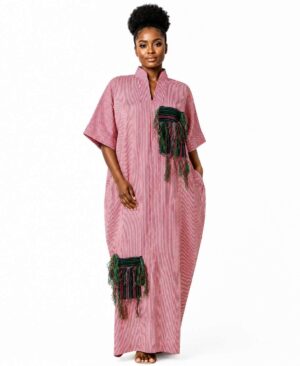 Full-length view of a woman wearing a red and white pinstripe African kaftan dress with green handwoven fringe patches.