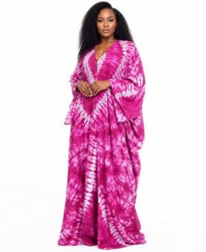 Full-length view of a woman wearing a vibrant fuchsia and white starburst tie-dye kaftan with long batwing sleeves.