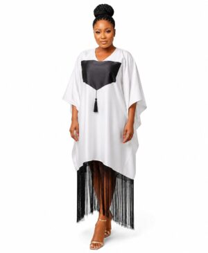 Woman wearing a white and black modern African kaftan dress with long black fringe at the hem and a chest tassel.