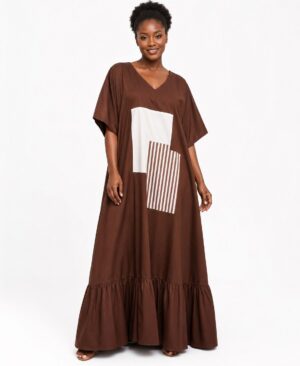 Woman wearing a floor-length chocolate brown kaftan dress with a cream geometric patchwork design and ruffled hem.