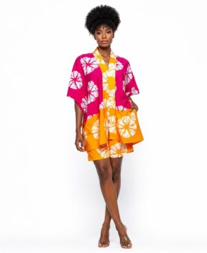 Woman wearing a vibrant pink and orange African print kimono and matching shorts set against a white background.