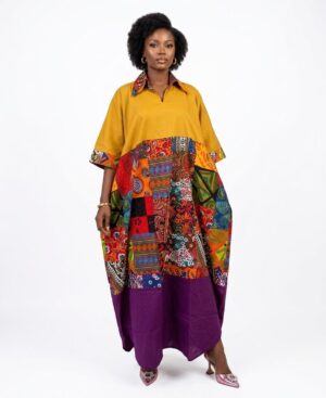 Woman wearing a mustard yellow and purple oversized Bubu dress with multi-colored Ankara patchwork mid-section against a white background.